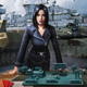 A woman dressed in military garb stands over battlefield plans as vehicles of war queue up behind her.